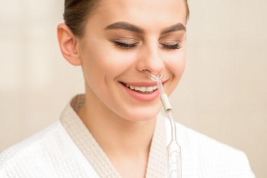 Beautiful happy young caucasian woman receiving nasal inhaler with essential oil smiling in a spa
