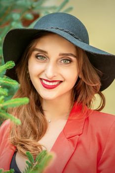 Portrait of a beautiful young caucasian woman with Christmas tree smiling and looking at camera