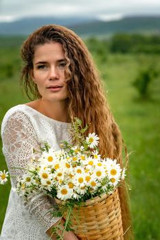 A middle-aged woman holds a large bouquet of daisies in her hands. Wildflowers for congratulations.