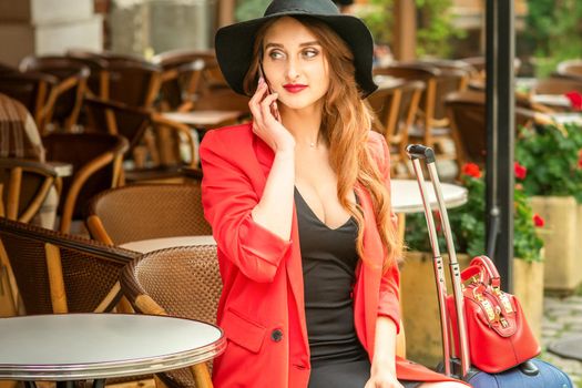 Beautiful travel young caucasian woman talking on phone while sitting in outdoor cafe