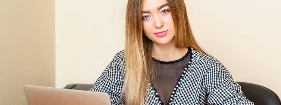 Portrait of a beautiful young caucasian woman sitting at the table looking at the camera in an office