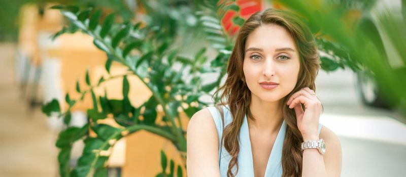 Portrait of a beautiful young caucasian woman sitting in flower garden outdoors