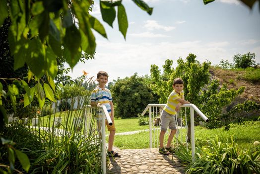 Summer adventure friendship childhood concept. Two children boy thinking secret plans or ideas on wooden bridge by stream in summer.