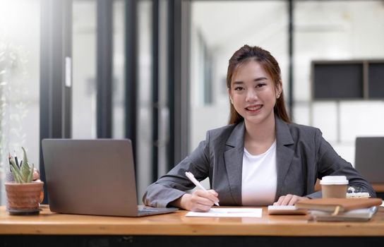 Asian businesswomn sitting working at the office. Looking at camera..