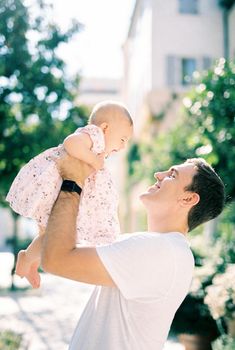 Smiling dad picks up a laughing little girl in his arms. Portrait. High quality photo