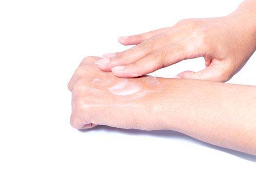 Closeup woman applying protective cream on hands. Cold season and dry air, applying lotion for preventing dry skin. Isolation in white background with clipping path.