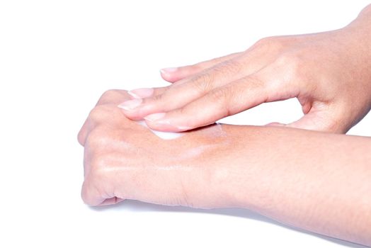 Closeup woman applying protective cream on hands. Cold season and dry air, applying lotion for preventing dry skin. Isolation in white background with clipping path.