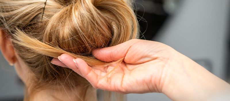 Close up of hands of female hairdresser styling hair of a blonde woman in a hair salon