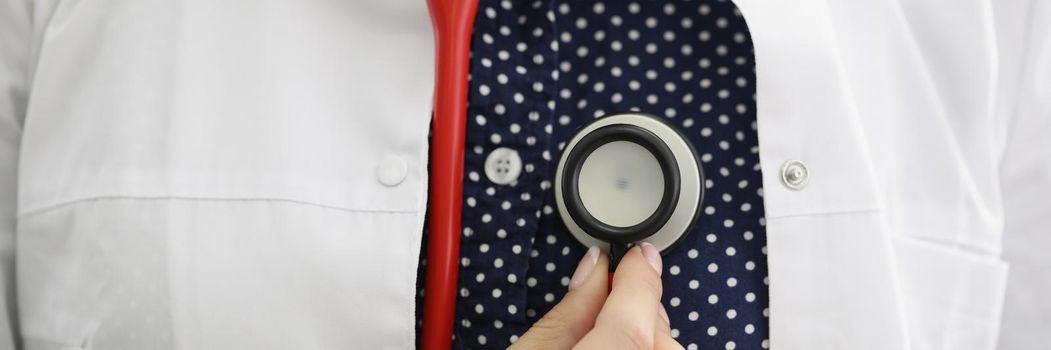 Doctor therapist holding stethoscope near his chest closeup. Heart disease diagnosis and treatment concept