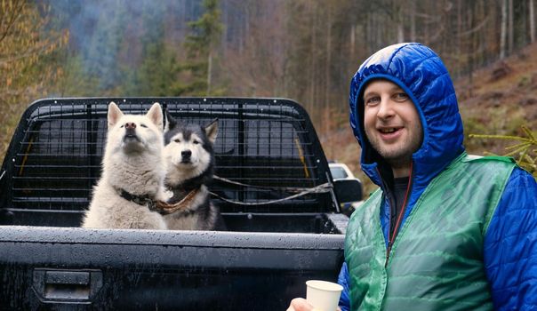 traveler with siberian tow beautiful husky dog in the wagon car. person with dog in the forset download photo