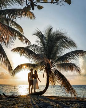romantic young couple together on beautiful exotic tropical beach under palms at sunset. download photo