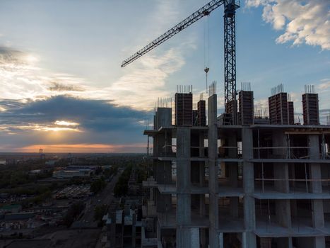 Construction site with cranes against the background of the evening sky. Turret slewing cranes working at sundown at evening time, buildings under construction download photo