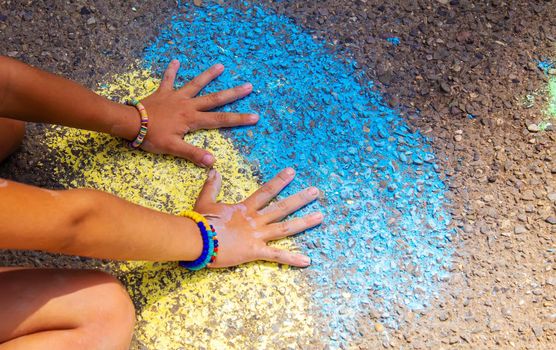 Children paint a rainbow on the asphalt. Selective focus. Kids.