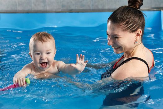Little child learning to swim in pool with a teacher
