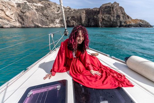 Attractive middle-aged woman in a red dress on a yacht on a summer day. Luxury summer adventure, outdoor activities