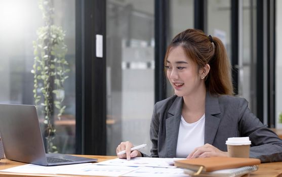 Beautiful Asian businesswoman work using a tablet and a laptop with documents placed at the office..