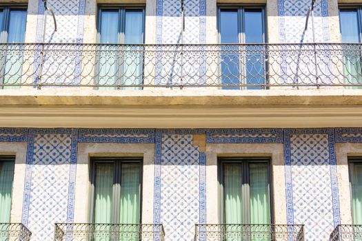 Beige facade of an old Portuguese house covered with blue azulejo tiles with windows and balconies