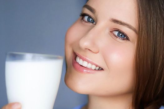 Happy young woman with glass of milk or protein milk shake, healthy cocktail drink for diet and wellness concept