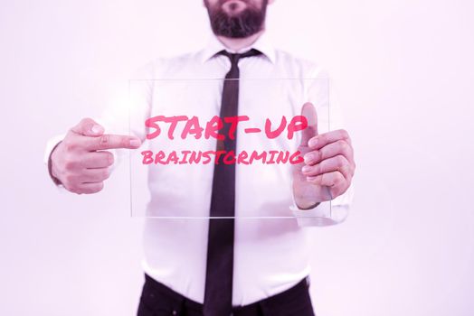 Sign displaying Start Up Brainstorming, Word Written on Team work for making strategies to a new business Businesswoman Holding Mobile Phone With Important Messages Sitting On Desk.