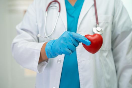 Doctor holding a red heart in hospital ward, healthy strong medical concept.