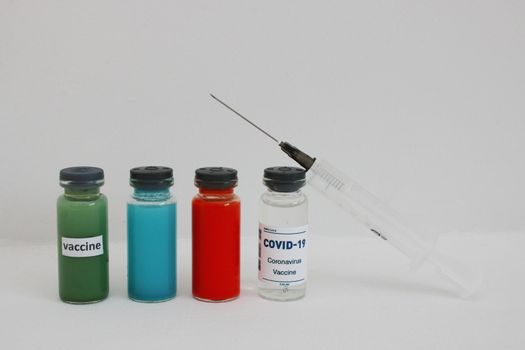 Four ampoules with vaccine and medicines and a syringe on a light background.