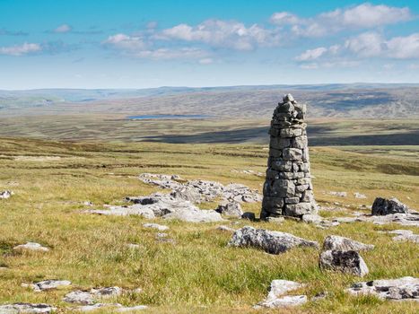 View over a tall cairn to Birkdale Tarn from a collection of stones known as the Millstones, Yorkshire Dales National Park, UK