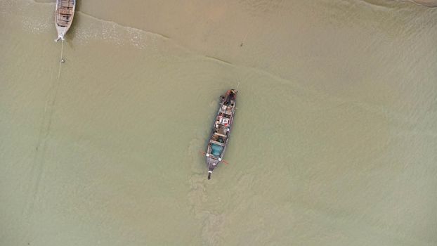 Aerial view from drones of fishing boats in the shore during low tide. Top view of Thai traditional longtail fishing boats in the tropical sea.