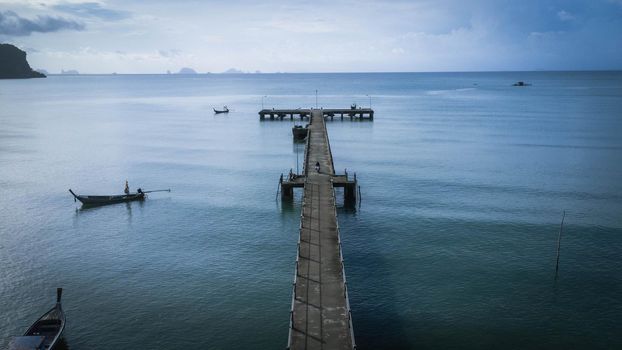 Aerial view from a drone of a pier in a tropical sea. A lot of Thai traditional longtail fishing boats in the sea.