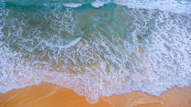 Beautiful sea waves and white sand beach in the tropical island. Soft waves of blue ocean on sandy beach background from top view from drones. Concept of relaxation and travel on vacation.