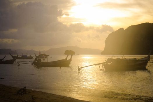 Beautiful scenery of fishing boats in the shore during sunset. A lot of Thai traditional longtail fishing boats in the tropical sea.