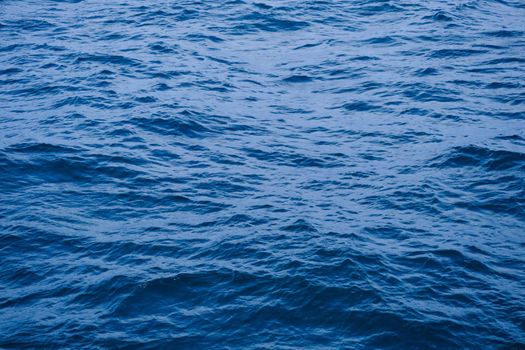 Background image of sea waves with sunlight reflected on the water surface. blue sea background in tropical sea