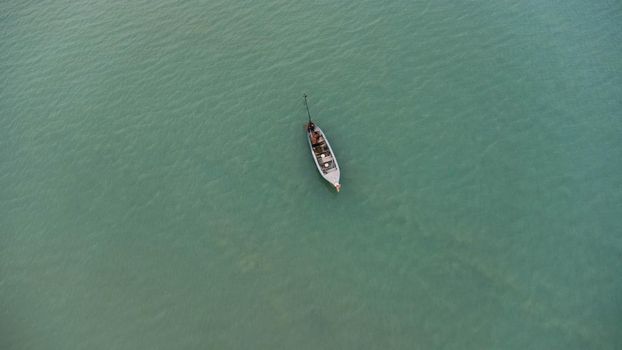 Aerial view from a drone of Thai traditional longtail fishing boats sailing in the sea. Top view of a fishing boat in the ocean.