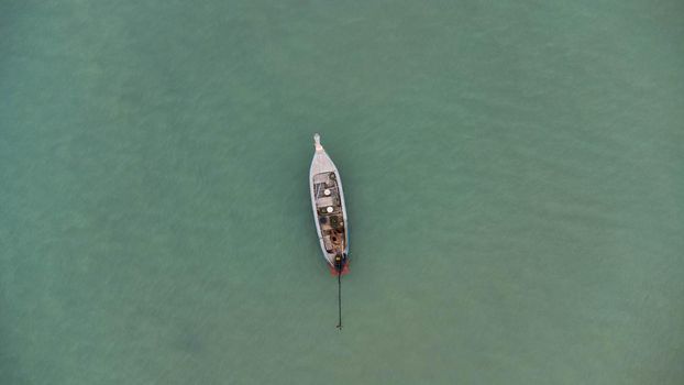 Aerial view from a drone of Thai traditional longtail fishing boats sailing in the sea. Top view of a fishing boat in the ocean.