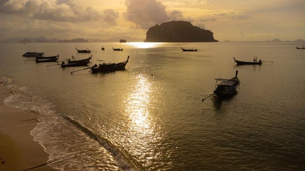 Aerial view from drones of fishing boats in the shore during sunset. Top view of many Thai traditional longtail fishing boats in the tropical sea.