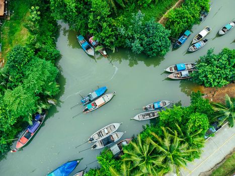 Aerial view from drones of fisherman boats and harbour in the river near the Andaman Sea in southern Thailand. Top view of many Thai traditional longtail boats floating in the mangrove landscape.