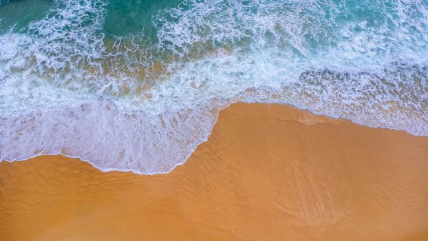 Beautiful sea waves and white sand beach in the tropical island. Soft waves of blue ocean on sandy beach background from top view from drones. Concept of relaxation and travel on vacation.