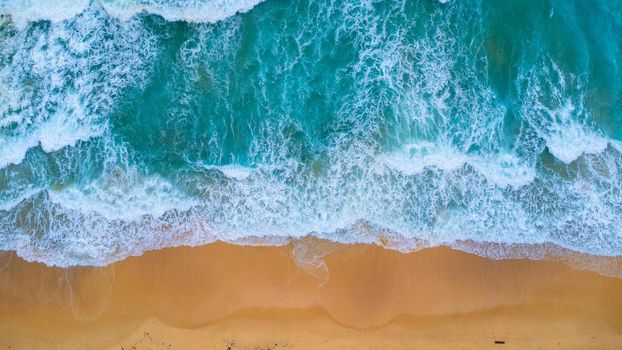 Beautiful sea waves and white sand beach in the tropical island. Soft waves of blue ocean on sandy beach background from top view from drones. Concept of relaxation and travel on vacation.