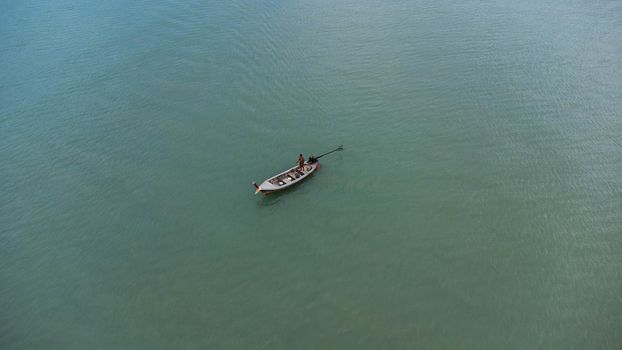 Aerial view from a drone of Thai traditional longtail fishing boats sailing in the sea. Top view of a fishing boat in the ocean.