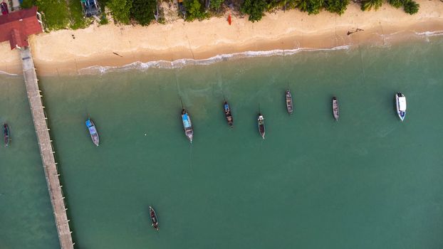 Many fishing boats near the seashore in tropical islands. Pier of the villagers on the southern island of Thailand. top view from drones.