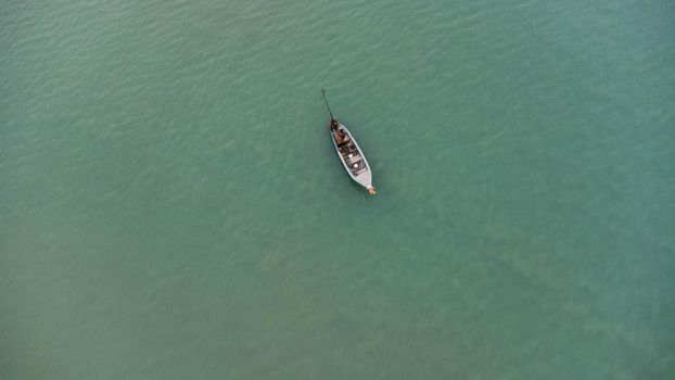 Aerial view from a drone of Thai traditional longtail fishing boats sailing in the sea. Top view of a fishing boat in the ocean.