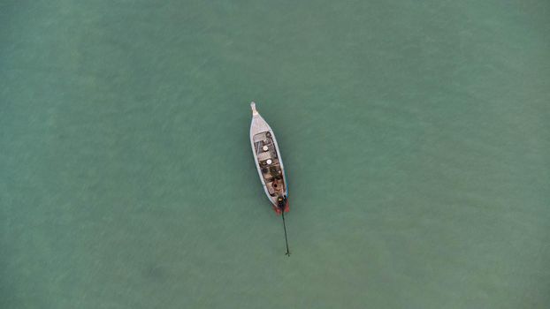 Aerial view from a drone of Thai traditional longtail fishing boats sailing in the sea. Top view of a fishing boat in the ocean.