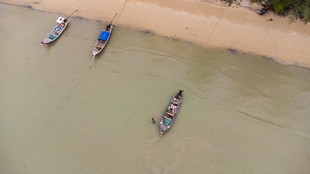 Aerial view from a drone of Thai traditional longtail fishing boats sailing in the sea. Top view of a fishing boat in the ocean.