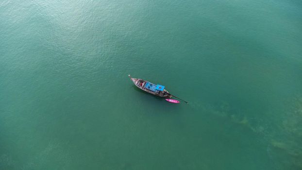 Aerial view from a drone of Thai traditional longtail fishing boats sailing in the sea. Top view of a fishing boat in the ocean.