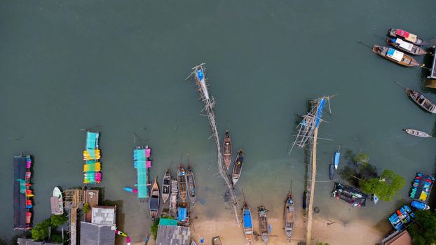 Aerial view from a drone of a pier in a tropical sea. A lot of Thai traditional longtail fishing boats in the sea.