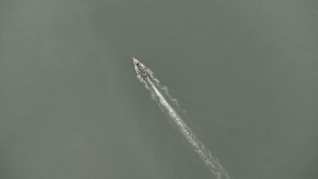 Aerial view from a drone of Thai traditional longtail fishing boats sailing in the sea. Top view of a fast moving fishing boat in the ocean.