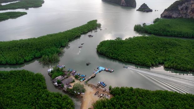 Aerial view of Thai traditional longtail fishing boats at the pier in Phang Nga Bay in the Andaman Sea, Thailand. Top view of many fishing boats floating in the sea among mangrove forest.