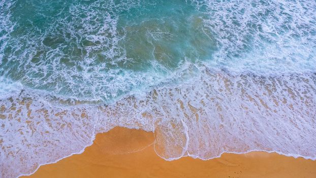 Beautiful sea waves and white sand beach in the tropical island. Soft waves of blue ocean on sandy beach background from top view from drones. Concept of relaxation and travel on vacation.