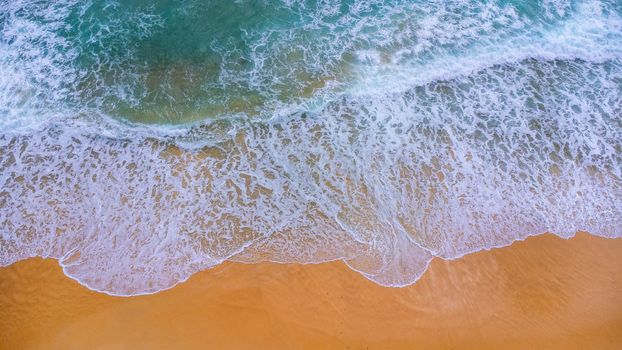 Beautiful sea waves and white sand beach in the tropical island. Soft waves of blue ocean on sandy beach background from top view from drones. Concept of relaxation and travel on vacation.