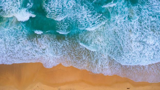 Beautiful sea waves and white sand beach in the tropical island. Soft waves of blue ocean on sandy beach background from top view from drones. Concept of relaxation and travel on vacation.