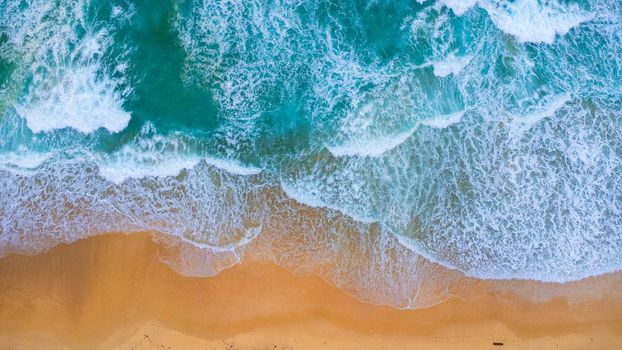 Beautiful sea waves and white sand beach in the tropical island. Soft waves of blue ocean on sandy beach background from top view from drones. Concept of relaxation and travel on vacation.